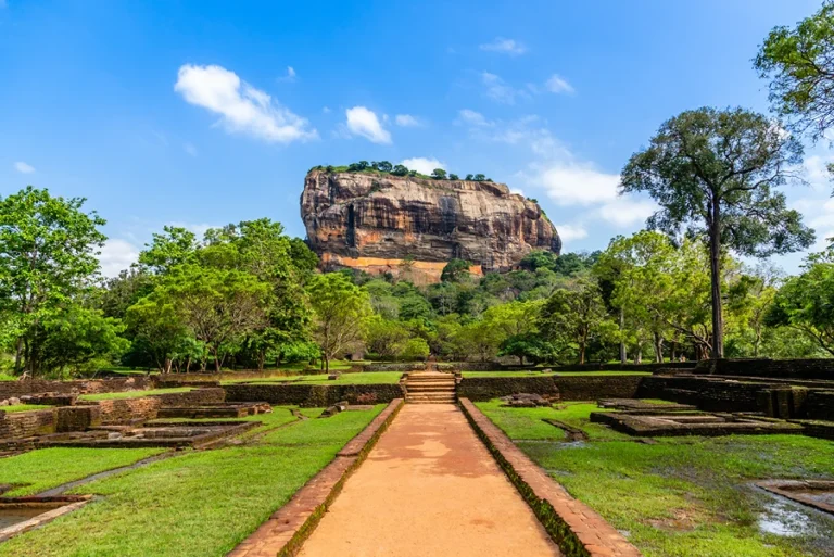 Majestic view of Sigiriya Rock Fortress rising above lush green forest under a blue sky in central Sri Lanka