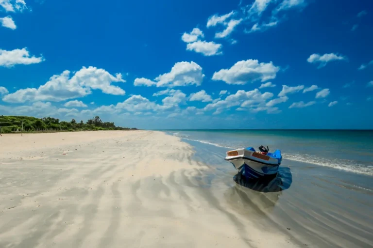 Traditional fishing boat resting on the wide sandy beach of Trincomalee under clear skies in eastern Sri Lanka